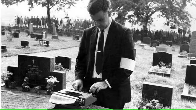Mann med skrivemaskin pa kirkegard