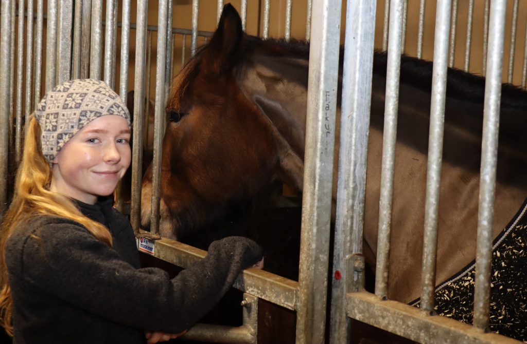 Leah Solberg viser hesten sin i stallen.