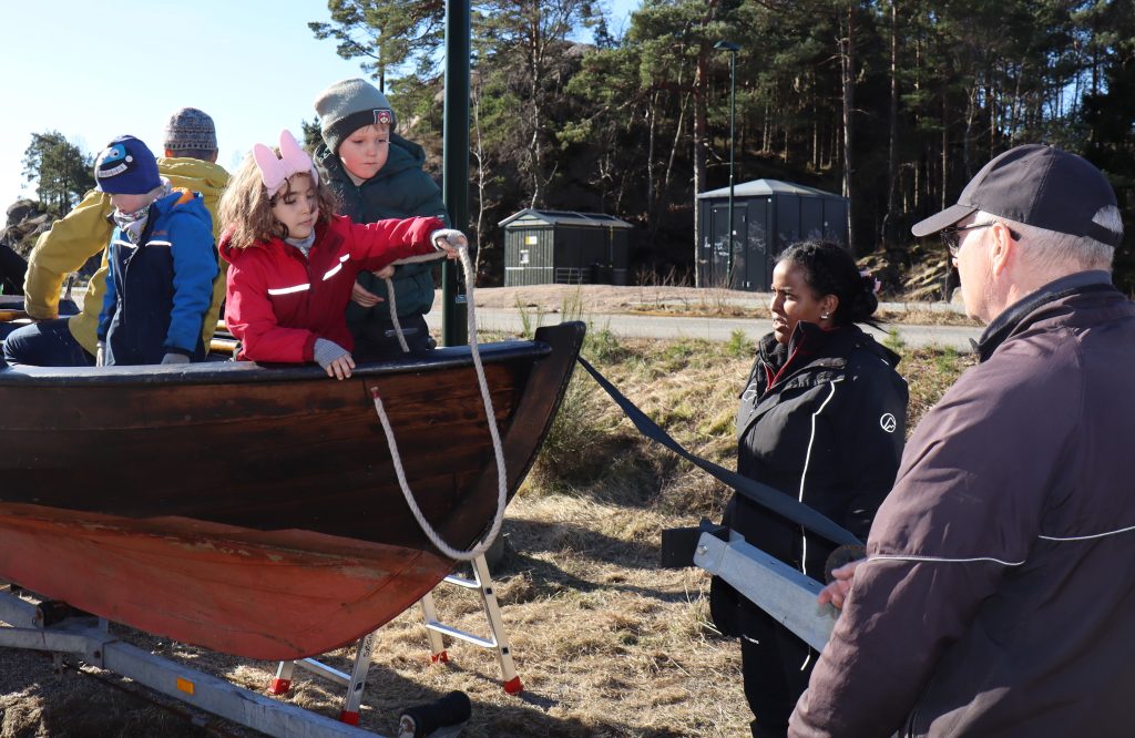 Sara kaster tauet "tampen" på land til Karl som tar i mot og fester tauet. Mio hjelper til, og Reeham fra barnehagen passer på.