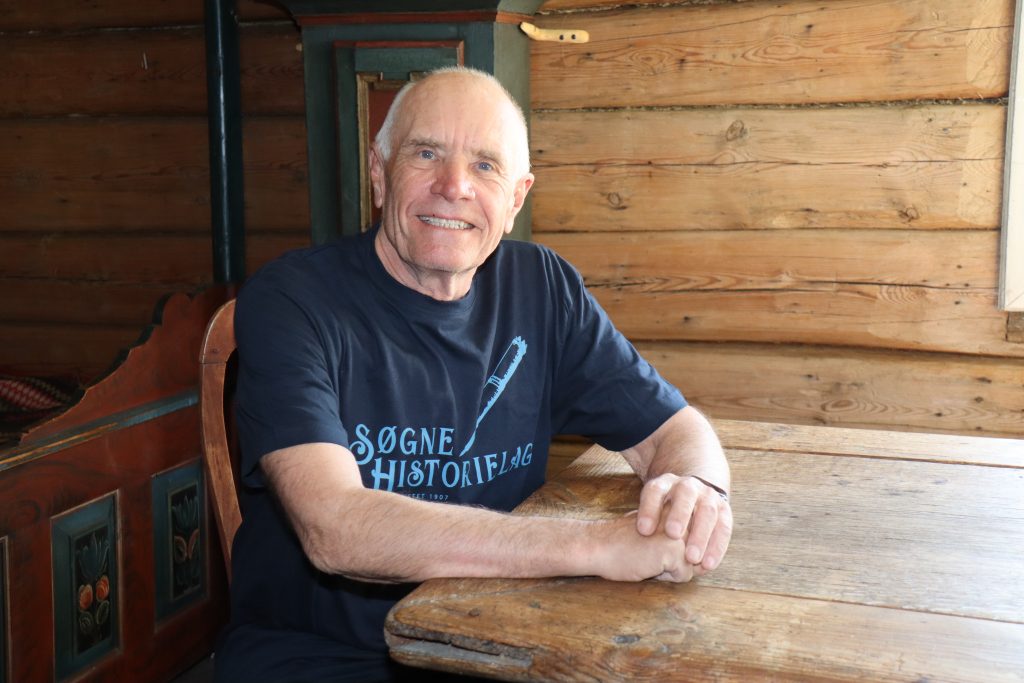 Søgne historielag inviterer til Historisk kafé! 1 – Det er første gang vi prøver oss på historisk kafe, og vi er spente på om det dukker opp noen. Vi ønsker å bidra til å skape litt aktivitet på Søgne gamle prestegård, i tillegg til å fokusere på lokalhistorie, forteller Kjell, her godt plassert ved langbordet i Søgne Bygdemuseum.