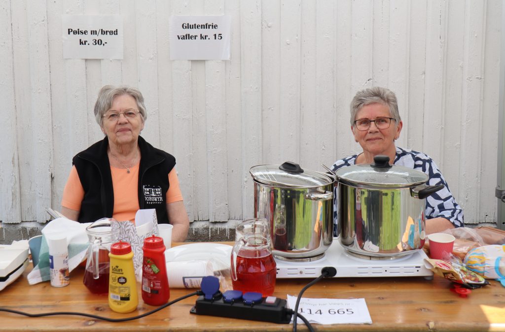 Bygdefest på Porsmyr! 10 Bak pølsegrytene sitter Turid Fløystøl (til venstre) og Aud Spikkeland. De synes salget går bra, og Turid nyter selv en pølse da vi stikker innom.