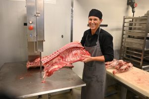 Elise Holmen skjærer opp et lam. Hun holder opp ribbene, som skal saltes og tørkes til pinnekjøtt.