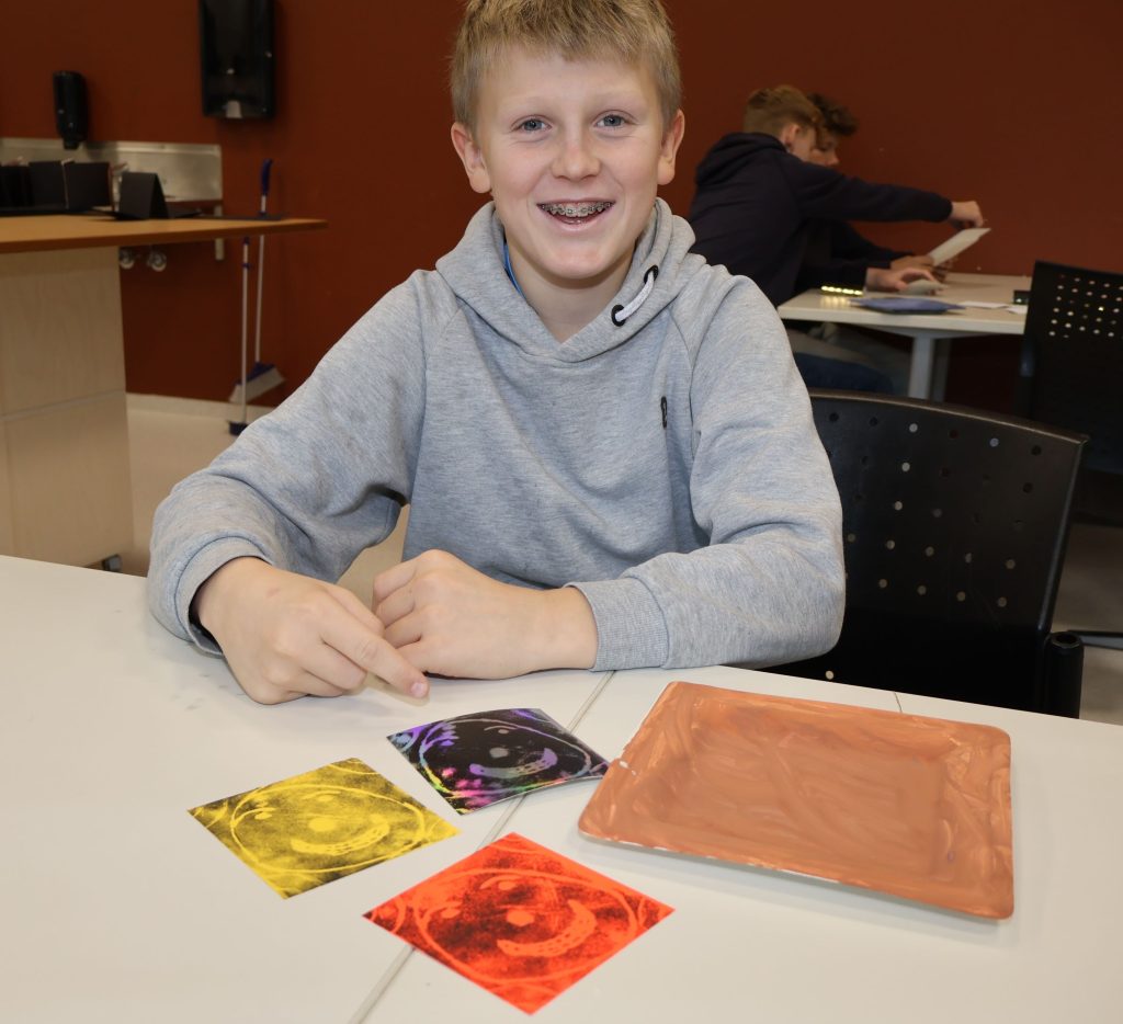 Linus viser sine grafiske kunstverk med smilefjes.